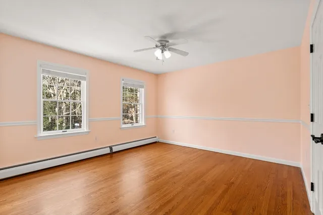 an empty room with wooden floor chandelier fan and windows