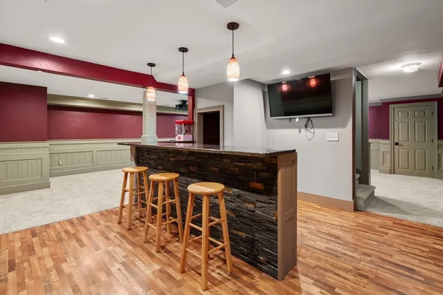 a kitchen with stainless steel appliances kitchen island granite countertop a stove top oven a sink dishwasher and a microwave with wooden floor