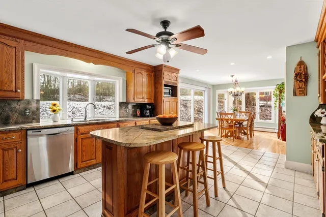 a kitchen with stainless steel appliances kitchen island granite countertop a table chairs sink and cabinets