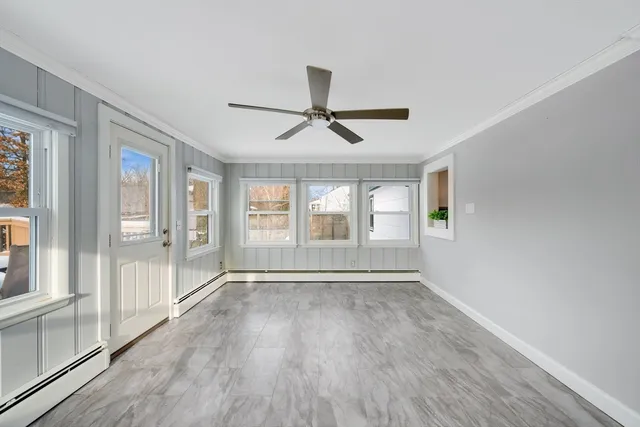 a view of an empty room with a window and wooden floor