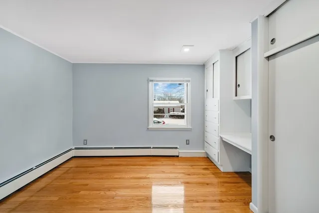 a view of an empty room with window and wooden floor