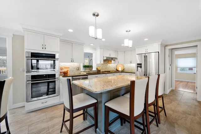 a kitchen with kitchen island granite countertop wooden floor cabinets and stainless steel appliances