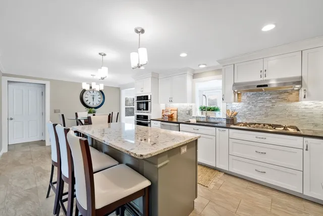 a kitchen with a dining table chairs cabinets and stainless steel appliances