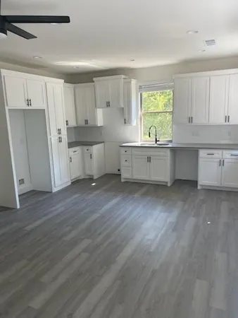 a large kitchen with a wooden floor and a window