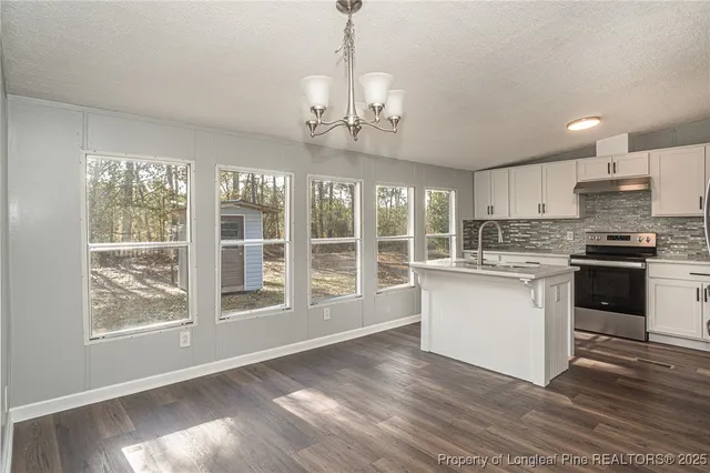 a kitchen with granite countertop wooden floors stainless steel appliances and a large window