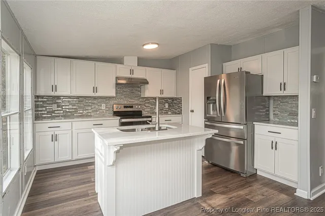a kitchen with granite countertop white cabinets and stainless steel appliances