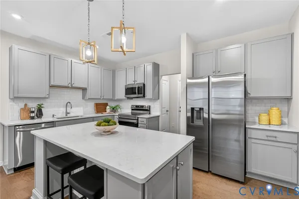 a kitchen with stainless steel appliances a refrigerator a sink a stove a table and chairs