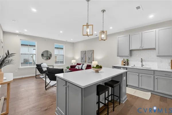 a view of a dining room and livingroom with furniture wooden floor a rug a flat screen tv a painting and a chandelier
