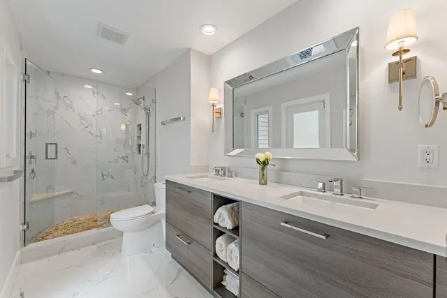 a spacious bathroom with a granite countertop sink a toilet a shower and a mirror