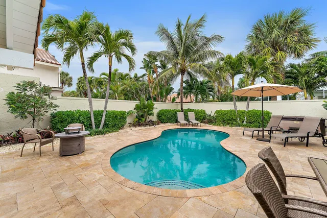 a view of a swimming pool with lawn chairs under an umbrella