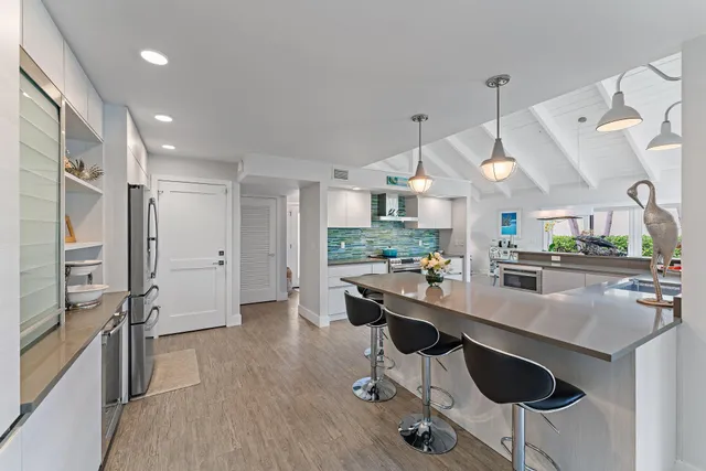 a kitchen with stainless steel appliances kitchen island granite countertop a table chairs in it and wooden floors
