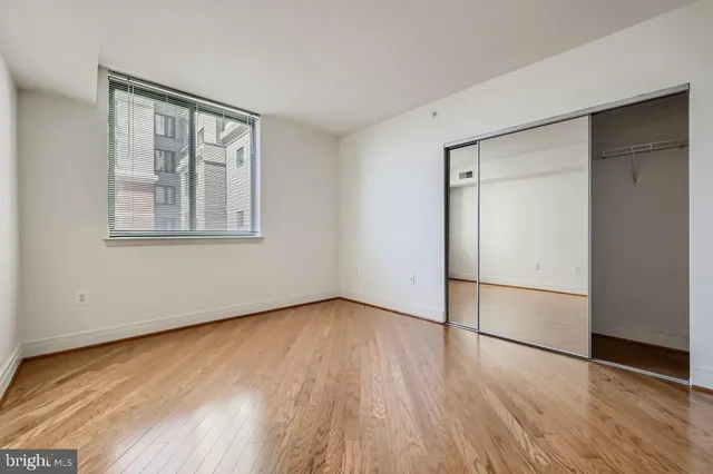 an empty room with wooden floor cabinet and windows