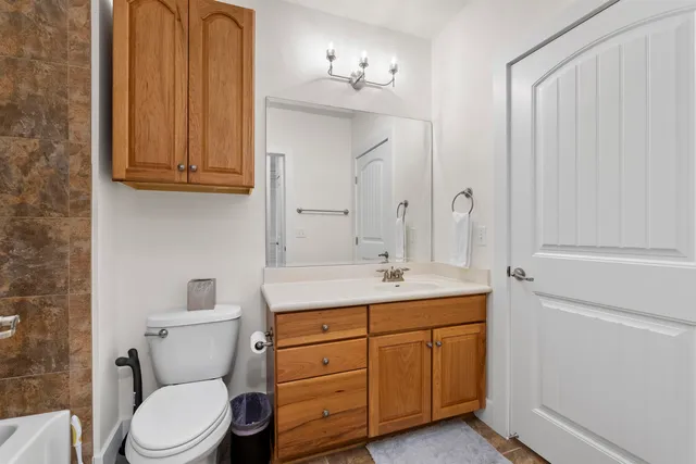 a bathroom with a granite countertop toilet sink and mirror