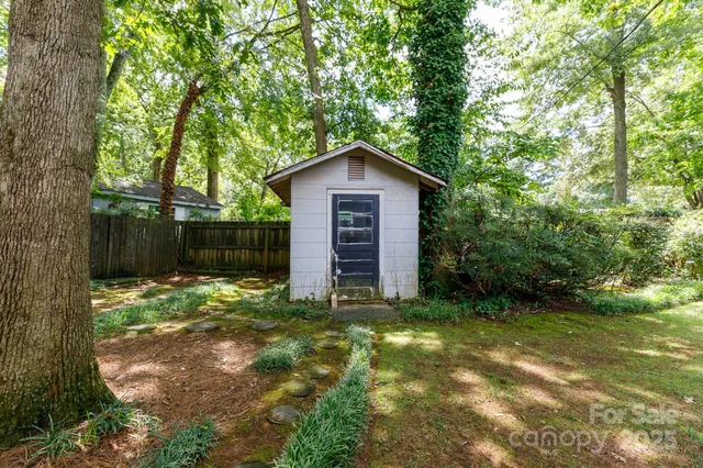 a view of backyard of a house with large trees and plants
