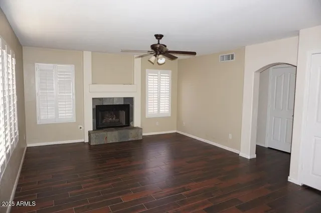 an empty room with wooden floor fireplace and windows