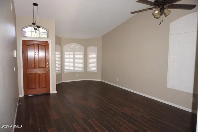 a view of a livingroom with wooden floor a ceiling fan and windows