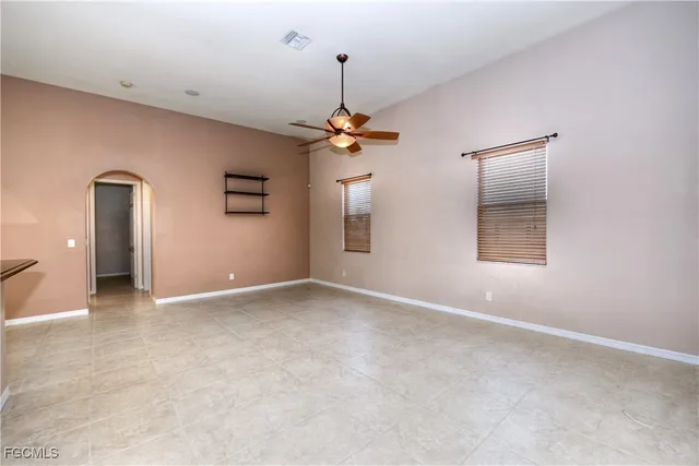 an empty room with chandelier fan and windows