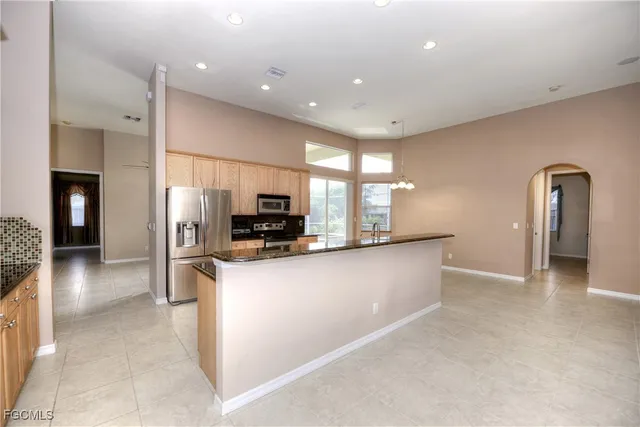 a large kitchen with stainless steel appliances granite countertop a refrigerator and a sink