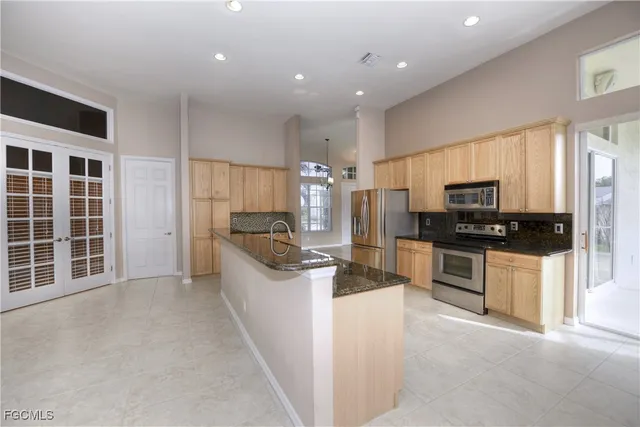 a kitchen with stainless steel appliances kitchen island granite countertop a stove a sink a refrigerator a window and white cabinets