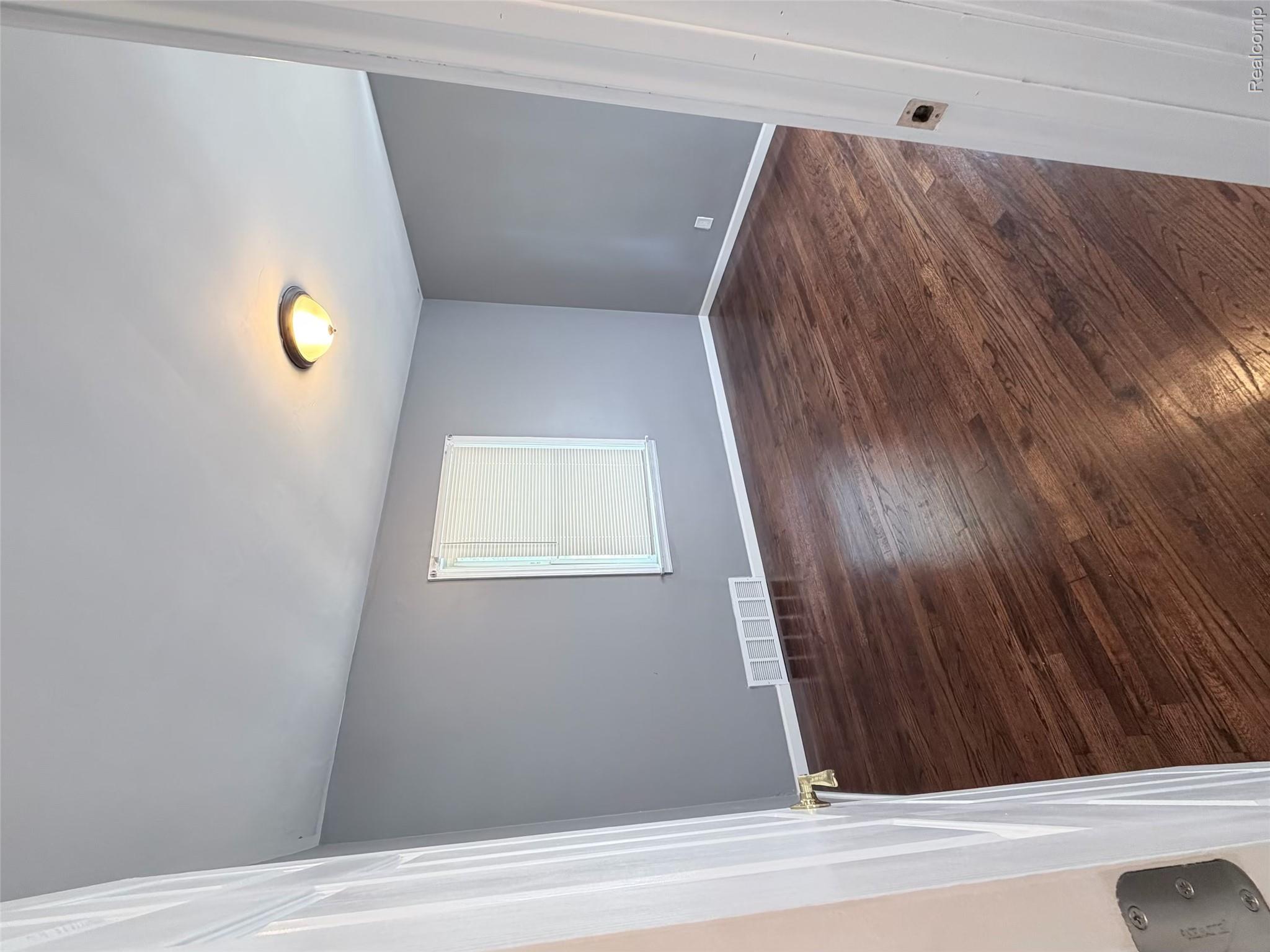 18467 Evergreen Road Detroit, MI 48219 - Photo 6 of 9 Bright, light-filled bedroom featuring rich wood-finish flooring, soft gray walls, and a large window with cellular shade