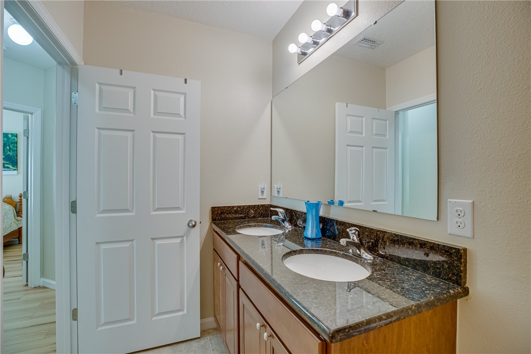 2965 Louetta Circle Melbourne, FL 32901 - Photo 27 of 36 a bathroom with a granite countertop sink and a mirror