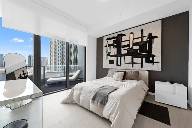 a large bedroom with a bed and glass wall