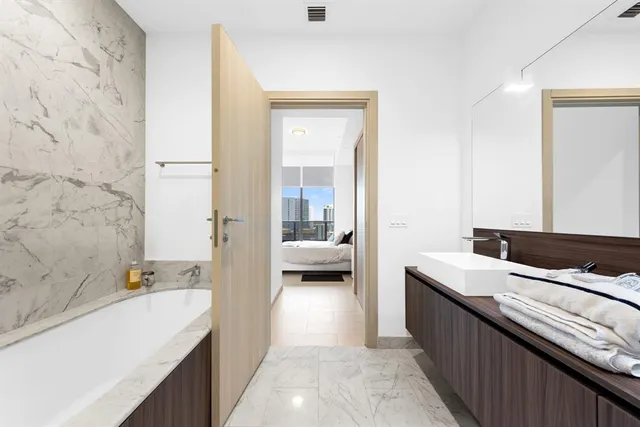 a en suite bathroom with a granite countertop tub a sink and a large mirror
