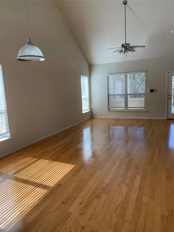 an empty room with wooden floor cabinet and windows