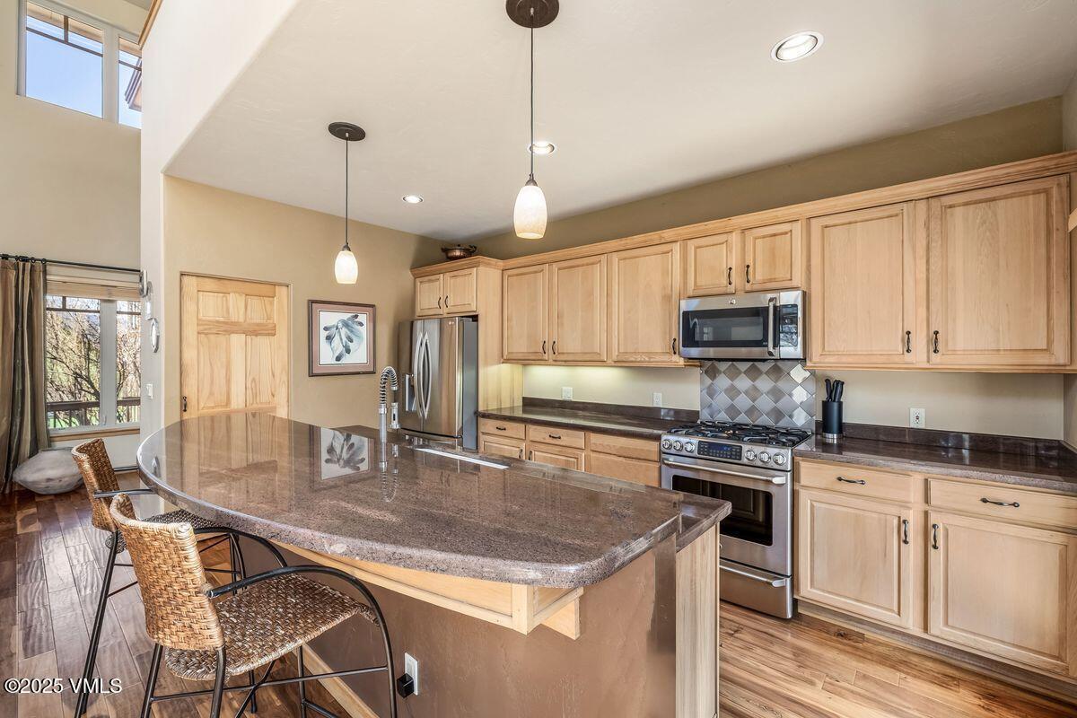 111 East Double Hitch Eagle, CO 81631 - Photo 6 of 38 a kitchen with stainless steel appliances granite countertop a stove a sink a microwave oven a refrigerator with white cabinets and wooden floor