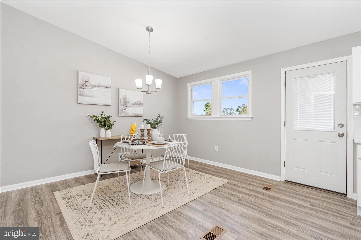 4609 Tema Road Pikesville, MD 21208 - Photo 8 of 36 a dining room with wooden floor a chandelier a wooden table and chairs