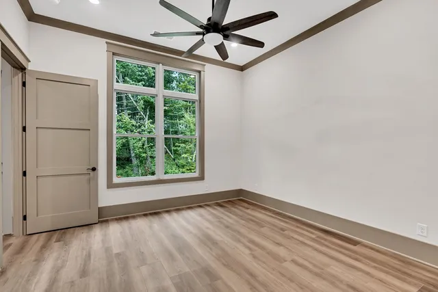 a view of empty room with wooden floor and fan