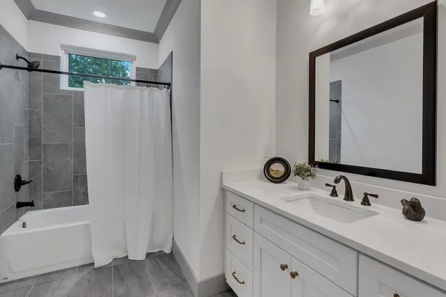 a bathroom with a double vanity sink mirror and bathtub