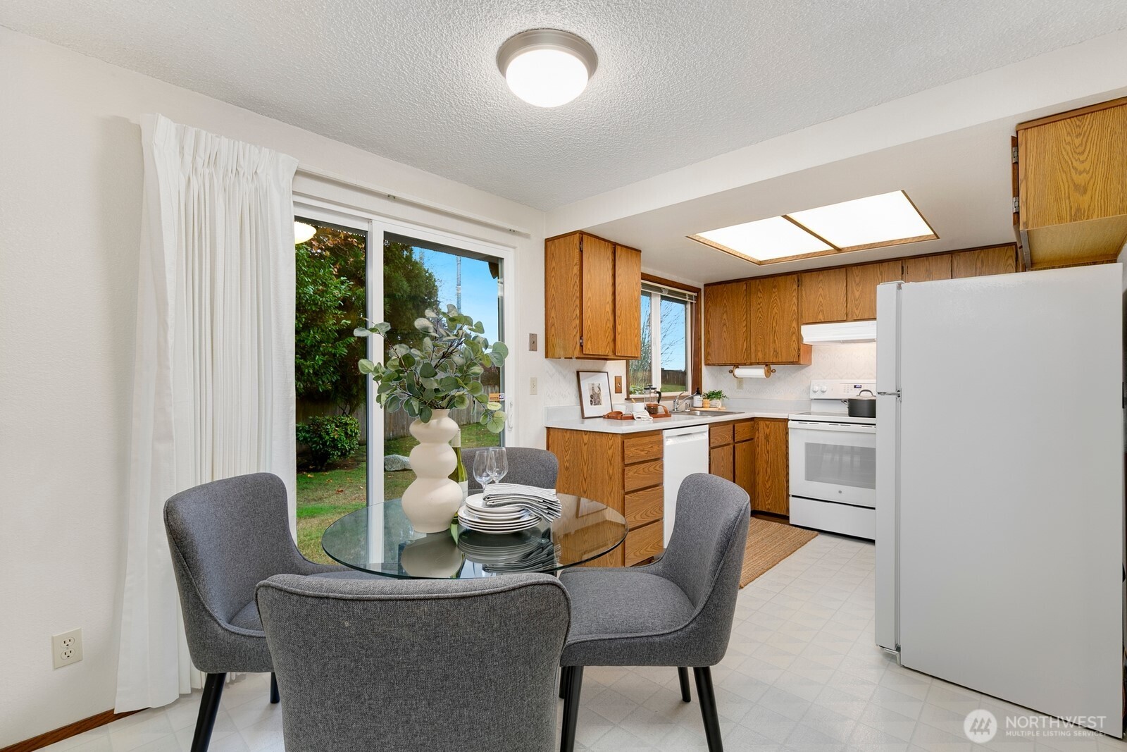 12903 Southeast 160th Street Renton, WA 98058 - Photo 6 of 24 a kitchen with a table chairs refrigerator and cabinets