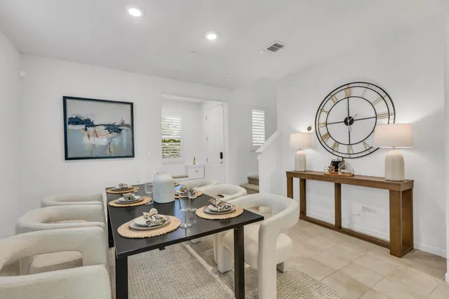 a open kitchen with stainless steel appliances granite countertop a stove top oven a sink dishwasher a dining table and chairs with wooden floor