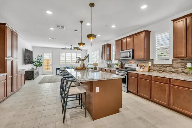 a kitchen with stainless steel appliances granite countertop a sink a stove and a wooden cabinets