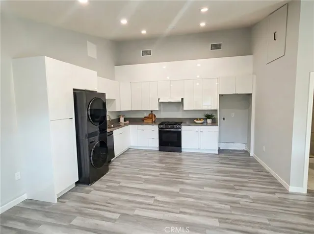 a large kitchen with a stove top oven a refrigerator and white cabinets