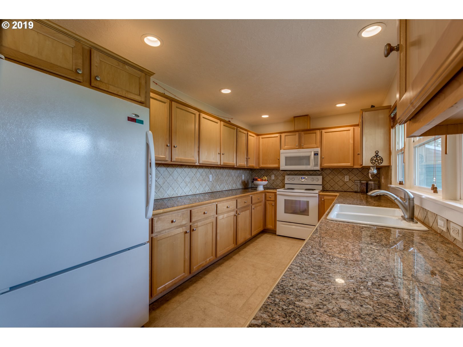 5859 Southwest Oleson Road Portland, OR 97225 - Photo 7 of 32 a kitchen with stainless steel appliances granite countertop a sink refrigerator and cabinets