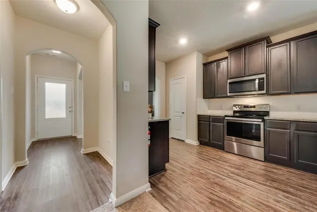 a kitchen with granite countertop wooden floors stainless steel appliances and sink