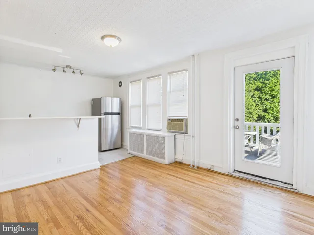 a view of empty room with wooden floor and window