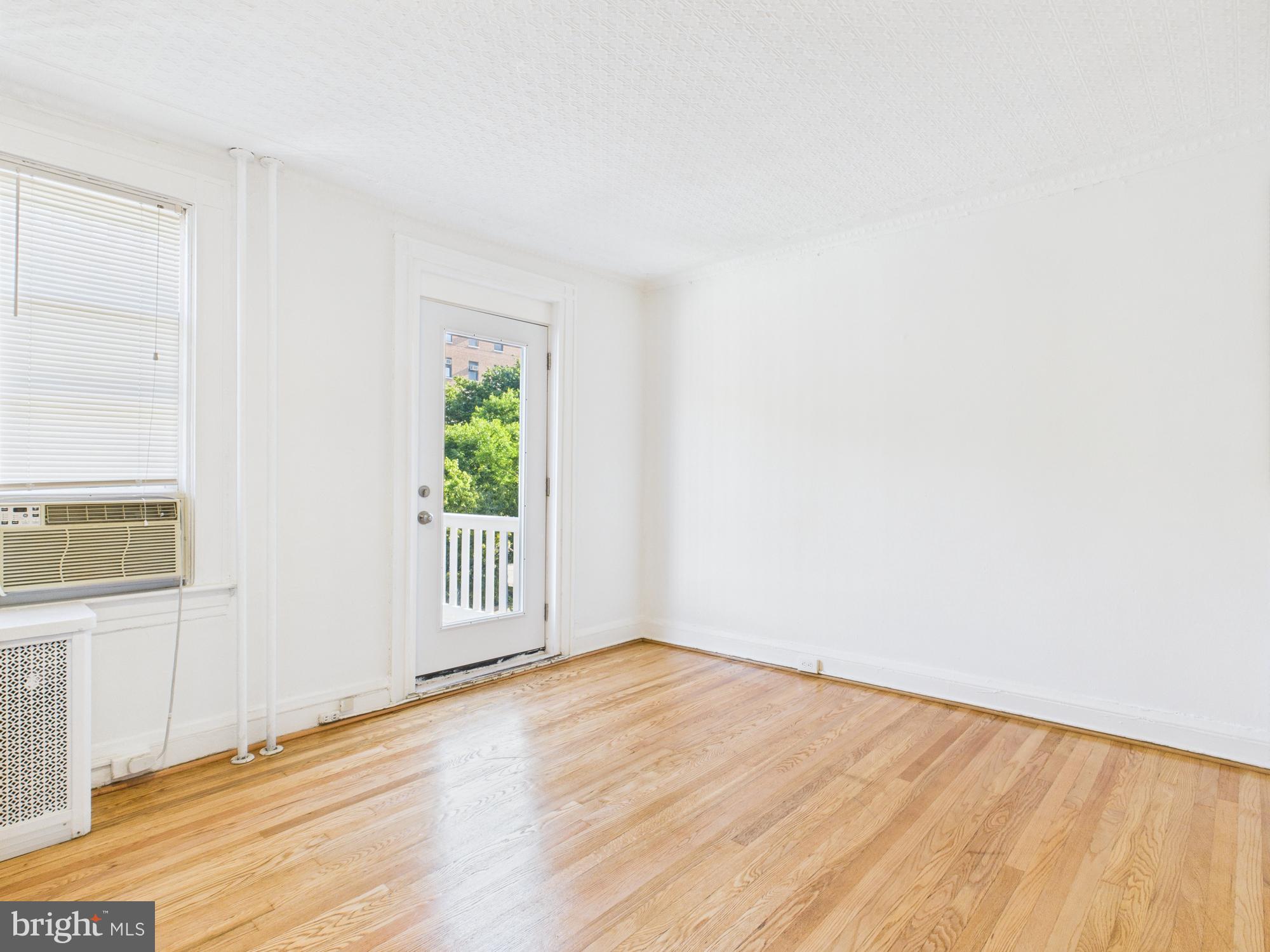 205 East 33rd Street, Unit 3 Baltimore, MD 21218 - Photo 2 of 18 a view of an empty room with wooden floor and a window