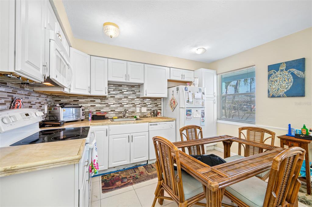 14111 West Parsley Drive Madeira Beach, FL 33708 - Photo 69 of 99 a kitchen with granite countertop a stove a sink dishwasher a dining table and chairs with wooden floor