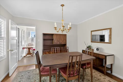 a view of a dining room with furniture a chandelier and wooden floor