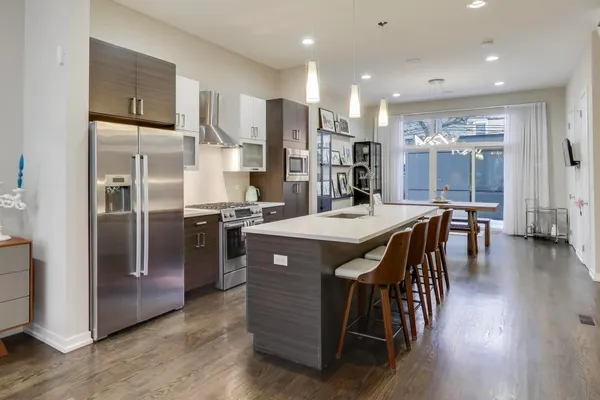 a kitchen with stainless steel appliances granite countertop a table chairs refrigerator and sink