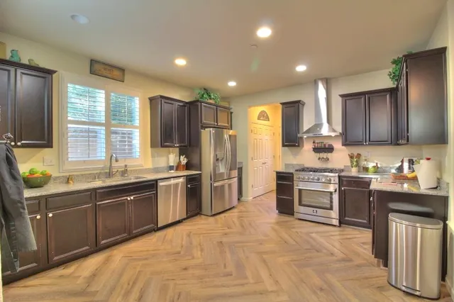 a large kitchen with stainless steel appliances granite countertop a stove refrigerator sink and dishwasher