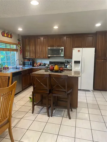 a kitchen with stainless steel appliances a stove a sink a refrigerator and chairs