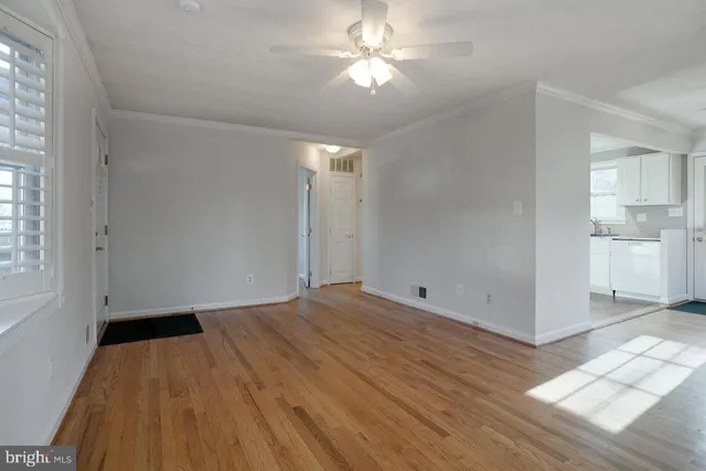 a view of empty room with wooden floor and fan