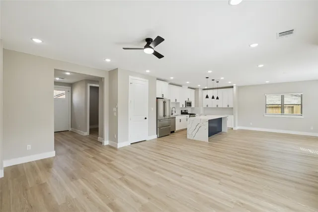 a view of a kitchen with kitchen island stainless steel appliances refrigerator stove and wooden floor