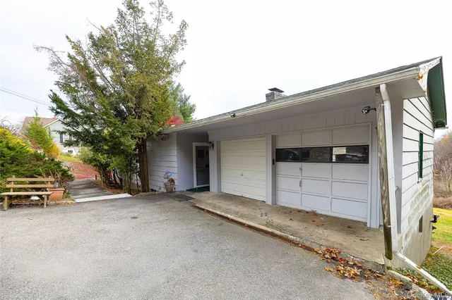 a tall yellow house with a big yard plants and trees in front of it