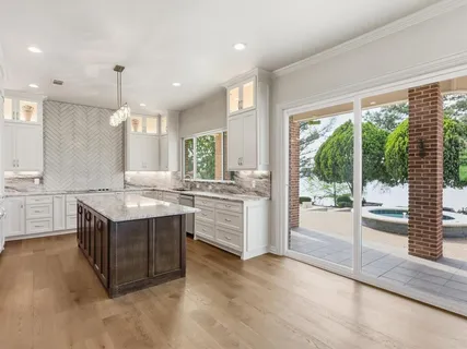 a large kitchen with granite countertop a large counter top space appliances and cabinets