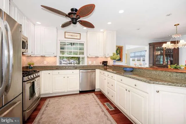 a kitchen with granite countertop a sink stainless steel appliances and window